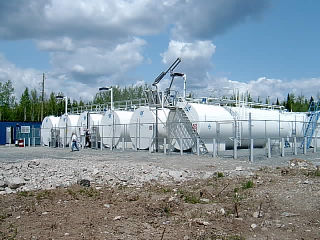 Several white tanks in a field.