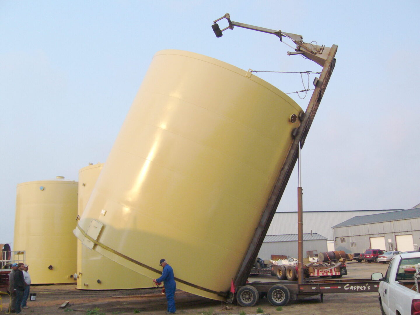 A large yellow tank being lifted onto a truck.