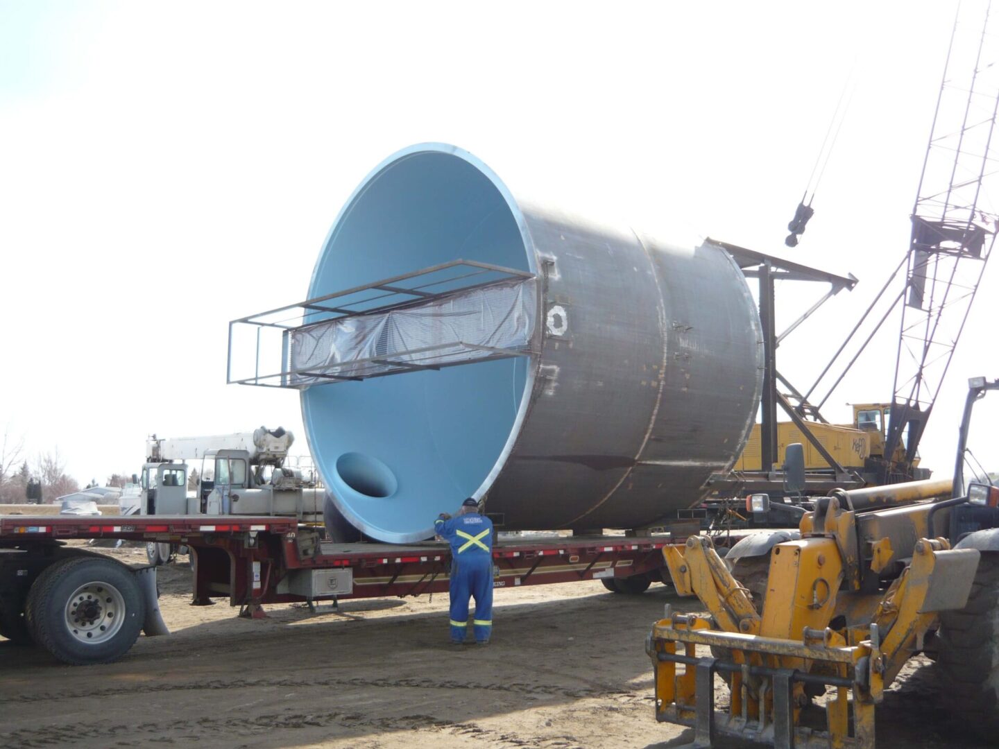 A large blue pipe being loaded onto a truck.