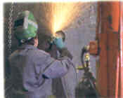 A man is welding in a room with a machine.