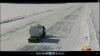 An aerial view of a truck driving down a snowy road.